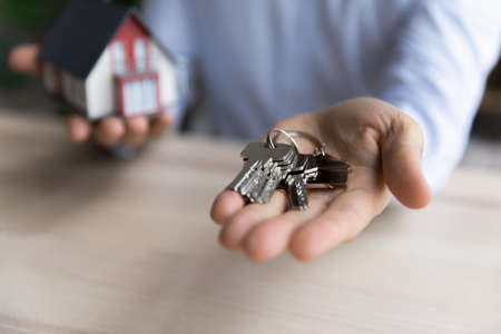 Real estate agent handing a house key to a new tenant in rental home.